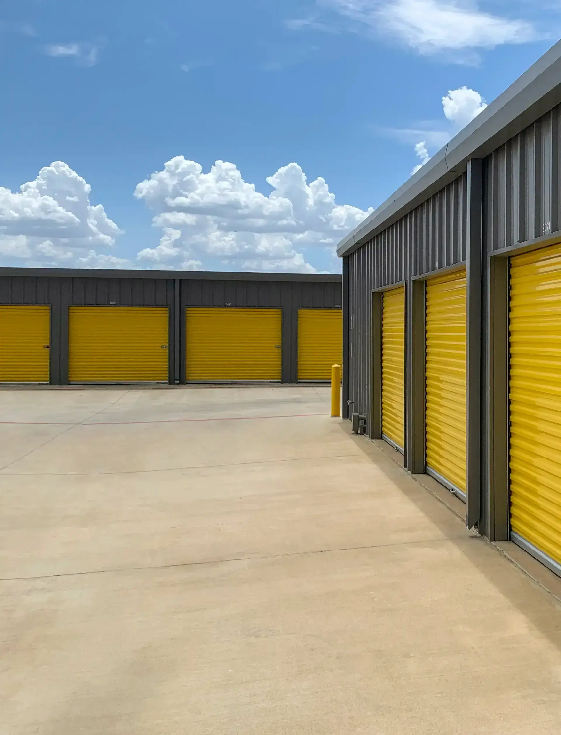 Outdoor shot of warehouses, storage facility, hangars or garages with yellow rolling gates
